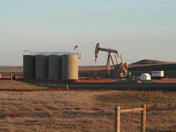 Oil and gas extraction site with storage tanks and pump jack